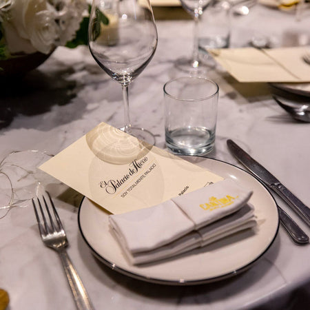 Montaje de mesa elegante con copa, cubiertos y plato con servilleta sobre mantel claro decorado.